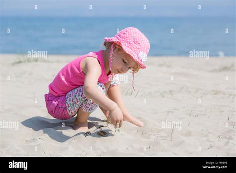 Junge blonde Mädchen spielen im Sand am Strand Stockfotografie Alamy