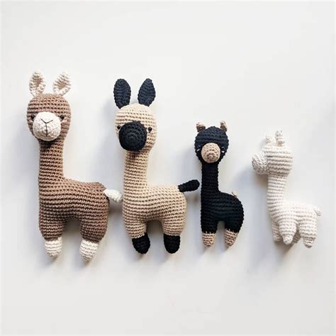 Three Crocheted Llamas Sitting Next To Each Other On A White Surface