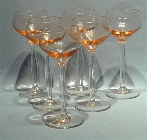 Five Wine Glasses Are Lined Up In A Row On A White Surface With Light