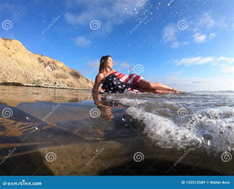 Un Modelo Moreno Precioso Poses Nude At La Costa Con Una Bandera Americana Imagen De Archivo