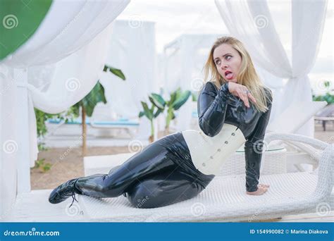 Jeune Fille Blonde Mince D Esclavage Dans La Combinaison Pantalon Noire De Latex Avec Le Corset