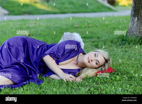 Beautiful Blonde With Long Hair And Long Purple Dress Is Having A White Wings And Looks Like An