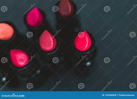 Group Of Red Pink And Nude Lipsticks With Different Colors And Textures On Dark Table Stock