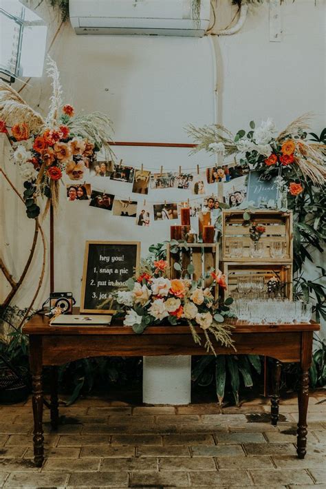 A Wooden Table Topped With Lots Of Flowers And Plants Next To A Wall