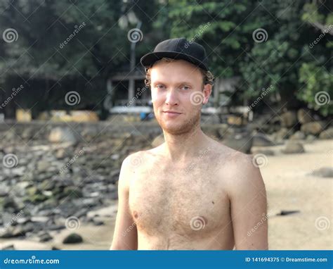 De Licht Gevilde Blonde Kerel In Een GLB Op Het Strand Zonder Tan Zonder Bovenkleding Glimlacht