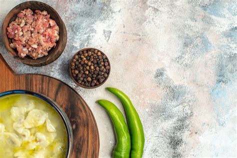 Free Photo Top Half View Dushbara On Chopping Board Bowls With Meat Black Pepper Hot Peppers