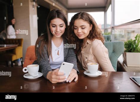 Two Girls Friend Drink Coffee In Cafe And Look In Smat Phone Happy