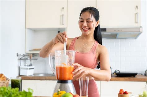 A Fit Asian Woman In Sportswear Making A Smoothie Or Healthy Juice In