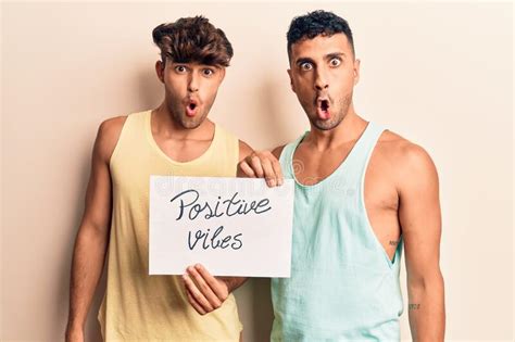 Joven Pareja Gay Sosteniendo Vibraciones Positivas Cartel Asustado Y Asombrado Con La Boca
