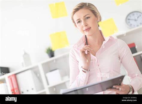 Une jeune fille blonde se tient au bureau près d un tableau transparent avec des autocollants et