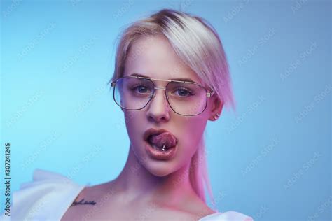 Closeup Portrait Of A Passionate Blonde Girl Wearing Glasses Poses With Tongue Sticking Out