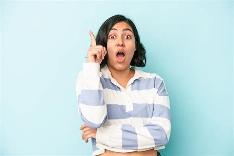 Mujer latina joven aislada sobre fondo azul que tiene una idea concepto de inspiración Foto