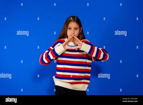 Pretty Preteen Brunette Hispanic Girl Wearing A Striped Sweater Making A Triangular Gesture With
