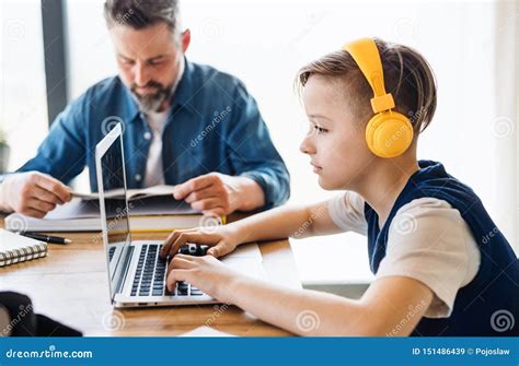 Mature Father With Small Son Sitting At Table Indoors Using Headphones And Laptop Stock Image