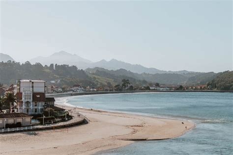 A Beach With Houses And Mountains In The Background