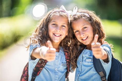 Twin sisters go back to school and showing thumbs up | Stock image ...