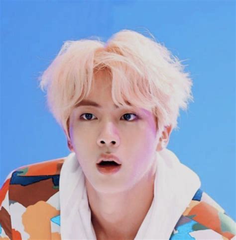 A Man With Blonde Hair And Blue Eyes Wearing A Colorful Shirt Looking