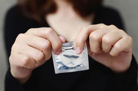 Premium Photo Condom Ready To Use In Female Hand Give Condom Safe Sex Concept On The Bed