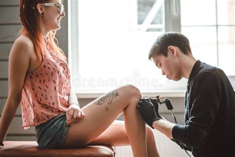 L Artiste Masculin De Tatouage Fait Un Tatouage Sur Une Jambe Femelle