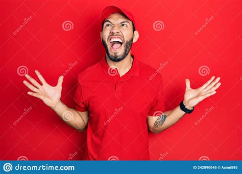 Hispanic Man With Beard Wearing Delivery Uniform And Cap Crazy And Mad