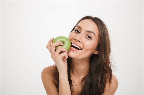 Free Photo Happy Brunette Woman Eating Apple And Looking At The Camera Over Gray