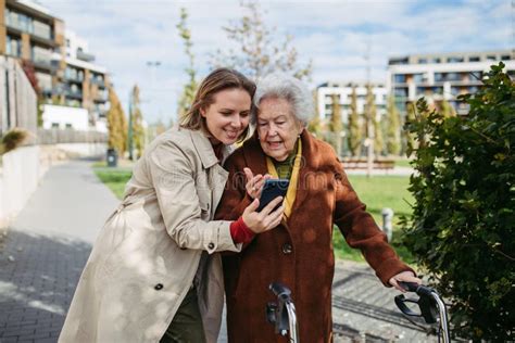 Mature Granddaughter Helping Grandmother Load Groceries In To The Car Senior Woman Shopping At