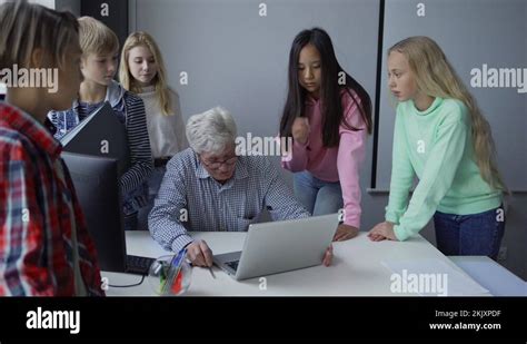 Mature Male Teacher Sitting In Front Of Laptop And Group Of Multiracial Pupil Stock Video