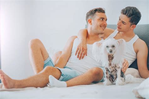 Joven Pareja Gay Riéndose Y Abrazándose En Su Cama Hombres Felices Y Su Perro Divirtiéndose