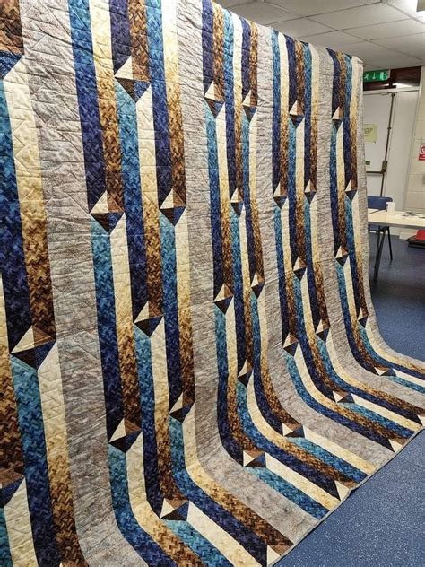 A Large Quilt Is Hanging On The Wall In An Office Area With Blue Carpeting