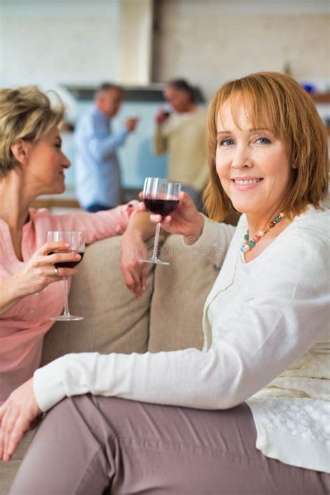 Mature Women Drinking Wine While Sitting In Sofa At Home Stock Photo