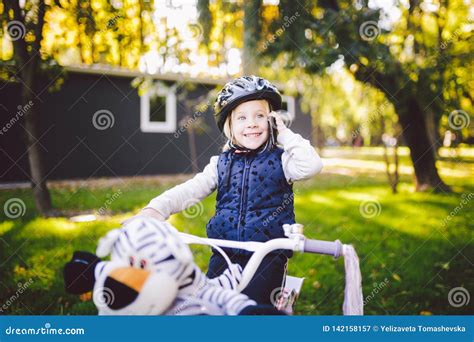 Het Grappige Blonde Van Het Kind Kaukasische Meisje In Een Fietshelm Dichtbij Een Purpere Fiets