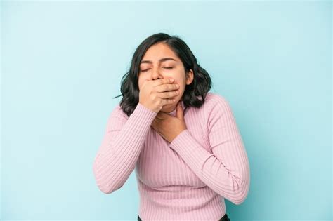 Joven latina aislada sobre fondo azul sufre dolor de garganta debido a un virus o infección