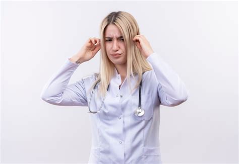 Médecin fatigué jeune fille blonde portant un stéthoscope et une robe médicale a mis ses mains