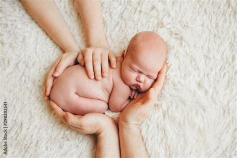 Naked Newborn Baby Lying On The Hands Of Parents On A White Background Imitation Of A Baby In