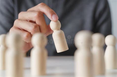 Man Hand Chooses Wooden Peg Doll Leadership And Business Team Creative