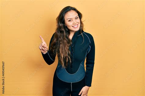 Young Hispanic Girl Wearing Diver Neoprene Uniform Pointing Finger Up With Successful Idea