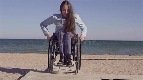 Young Disabled Woman In Wheelchair Moving By The Wooden Ramp For People