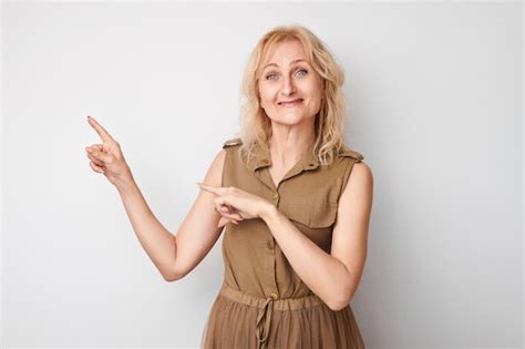 Belle femme mature de ans montrant le doigt de côté démontrant l espace vide pour le produit
