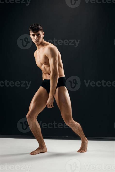 Man With Muscular Naked Body In Black Panties Posing Against Dark Background Stock