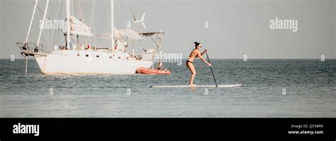 Sea Woman sup Silhouette einer glücklichen Frau mittleren Alters im Regenbogen Bikini Surfen