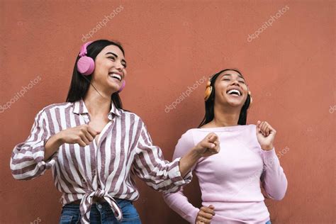 Feliz joven latina divirtiéndose bailando y escuchando música con auriculares inalámbricos