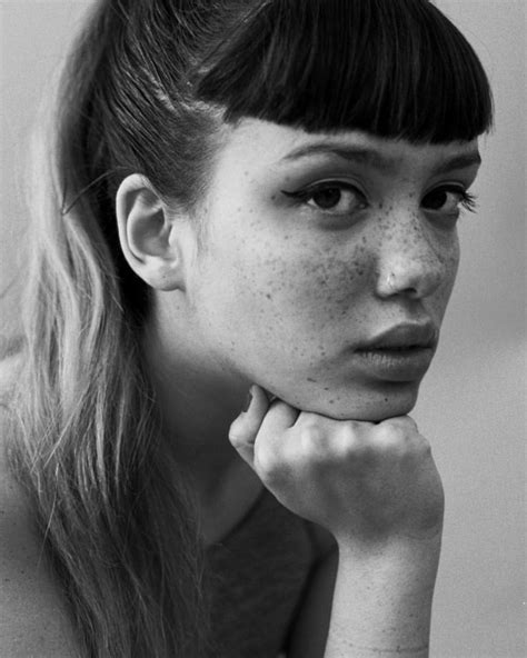 A Black And White Photo Of A Woman With Freckles On Her Face Looking At