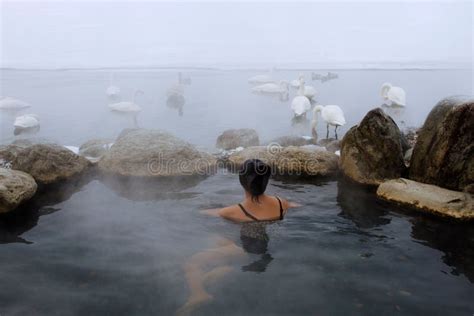 Woman Relaxing In A Hot Spring With Whooper Swans Swimming Around In Lake Kussharo Hokkaido