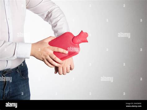 A Man Smoothes A Red Heating Pad With Hot Water On His Wrist Joint To Relieve Pain Treatment Of
