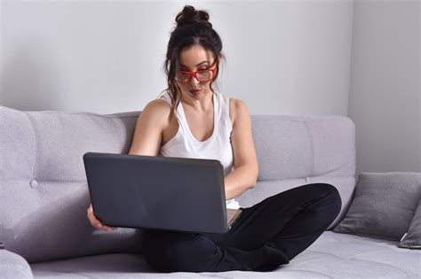 Premium Photo Beautiful Brunette Woman In Red Glasses On Sofa Using Laptop