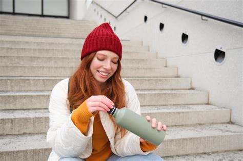 Free Photo Smiling Traveler Redhead Girl Tourist Sits On Stairs With Flask Drinks Hot Coffee