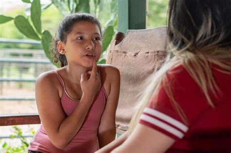 Rapariga bruneta latina mostrando a sua mãe a sua boca enquanto fala a sua mãe Foto Premium