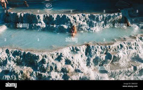 Blond Girl Relaxing At Natural Spa With Waterfalls And Hot Springs At Saturnia Thermal Baths
