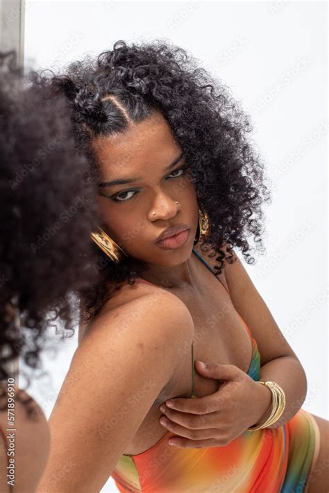 Mujer Joven Latina Con El Pelo Rizado Y Un Vestido De Tirantes De Varios Colores Posando Delante