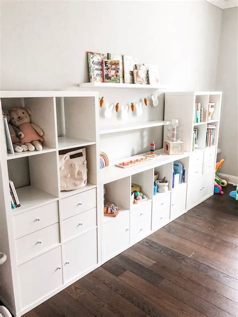 A White Bookcase Filled With Lots Of Books Next To A Wall Mounted Teddy